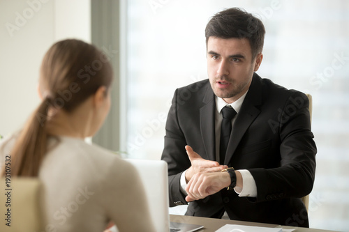 Foto Angry company head pointing at watch scolding female employee for being late at work, hurrying manager to finish important job before deadline