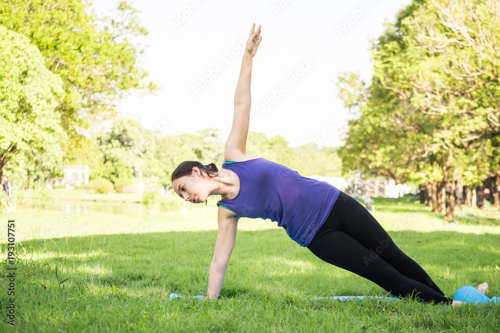 Fototapeta premium Beautiful woman doing yoga exercises in the park. Concept of healthy lifestyle.