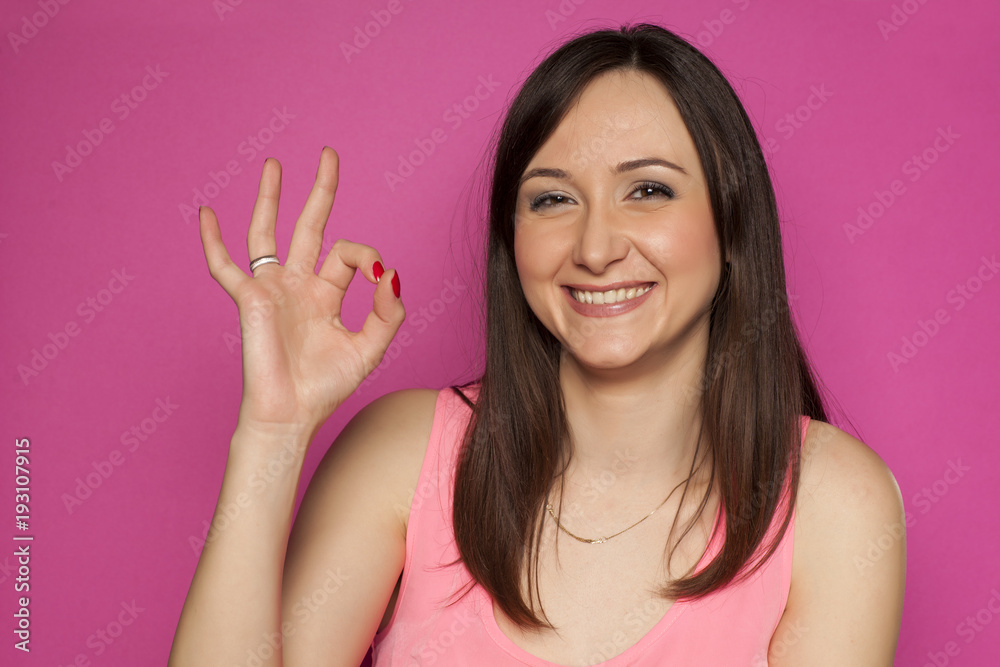 Young smiling woman with delicious gesture on pink background Young smiling woman with delicious gesture on pink background
