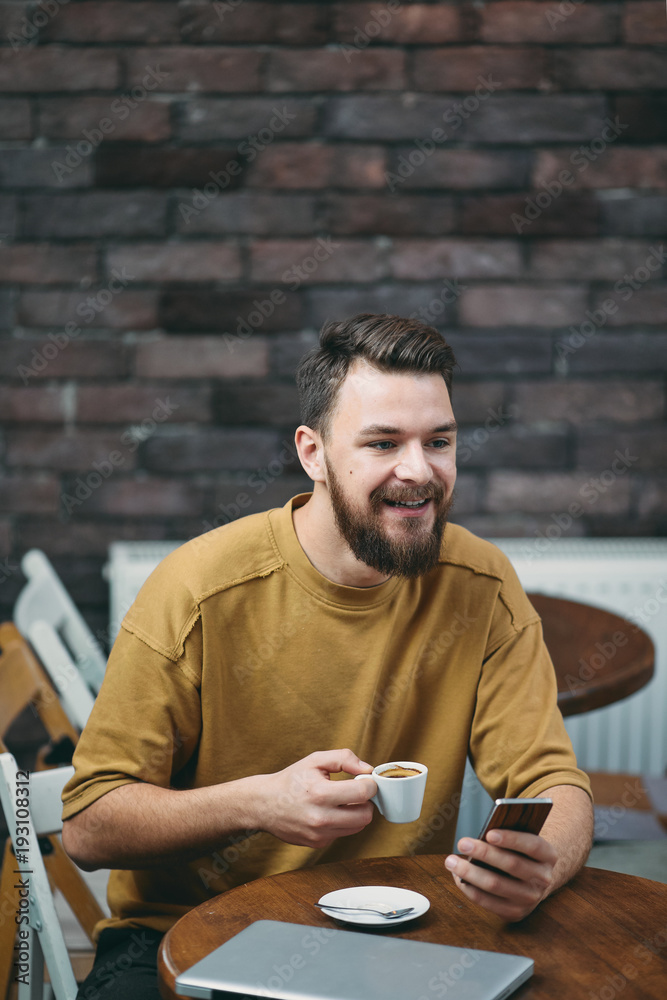 Young man sitting in cafe and using smart phone. Young man sitting in cafe and using smart phone.