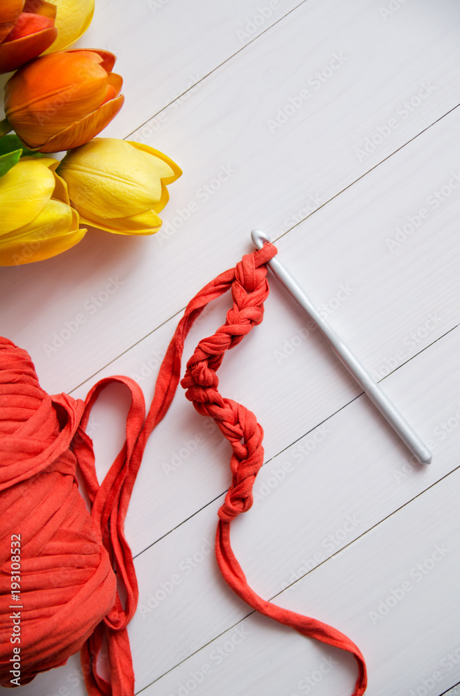 Crochet hook and a roll of cotton yarns on white wooden background. The concept of crochet, hobby, needlework, self-realization, creativity Crochet hook and a roll of cotton yarns on white wooden background. The concept of crochet, hobby, needlework, self-realization, creativity