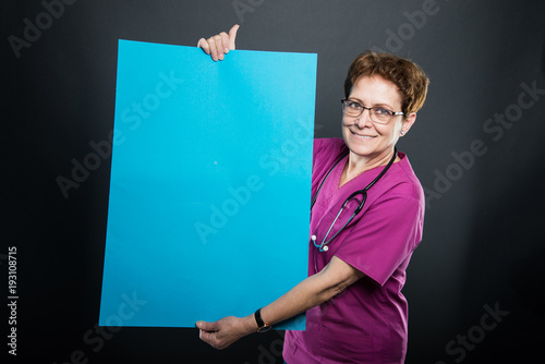 Portrait of senior lady doctor showing big blue board photo