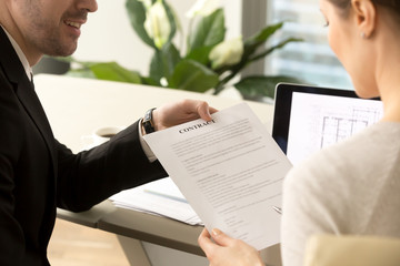 Male credit expert or real estate agent offering female client sign contract to buy apartments or house. Woman reading housing loan agreement and listening realtor, contractor representative advise