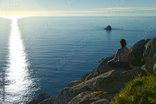 Young woman awaiting for sunset at Cape Fisterra or Finisterre, La Coruña, Galicia, Spain, Europe