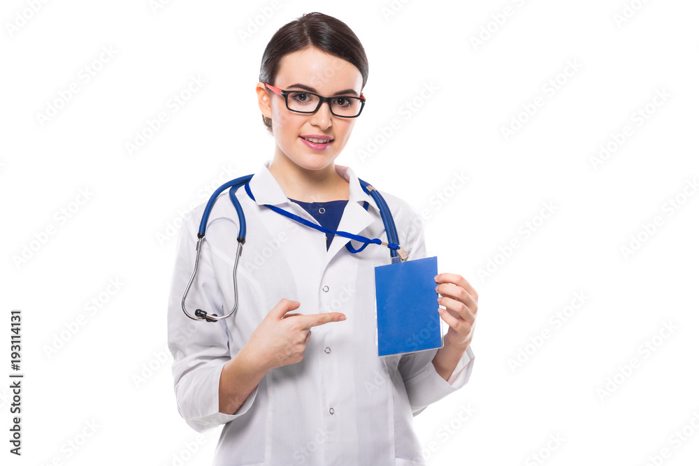 Young woman doctor with stethoscope holding badge in her hand and showing on her badge in white uniform on white background