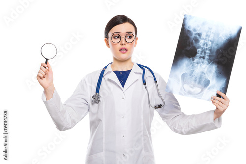 Young woman doctor with stethoscope looking at x-ray making diagnosis in white uniform on white background
