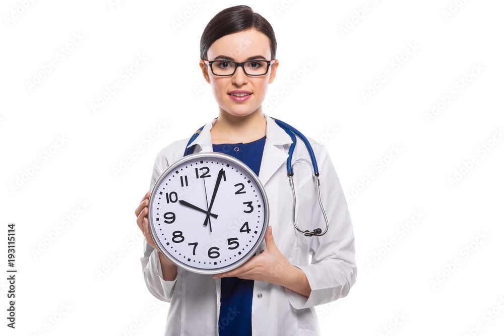 Young woman doctor with stethoscope holding clock in her hands in white uniform on white background Young woman doctor with stethoscope holding clock in her hands in white uniform on white background