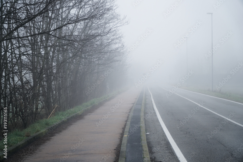 Asphalt road that goes through a misty foggy dark misterious pempty fields Asphalt road that goes through a misty foggy dark misterious pempty fields