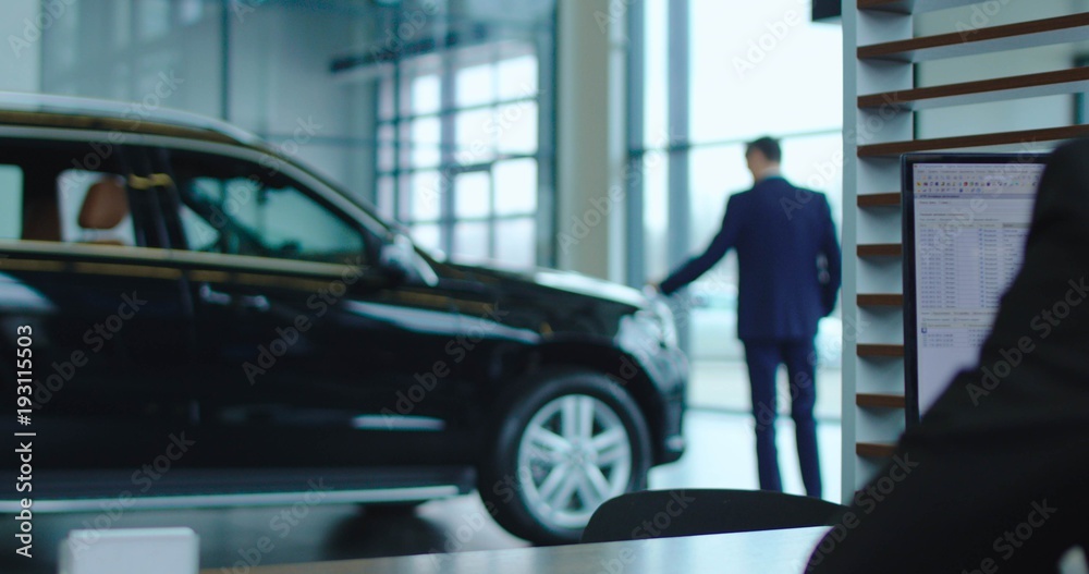 A man walks from the table of sales manager to his bought car