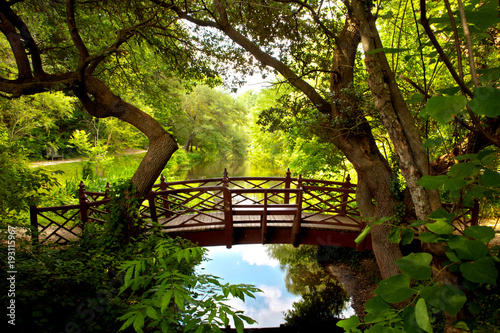 A romantic colonial bridge  in Williamsburg Virginia immersed in a green woodland with a beautiful reflecting water pond.