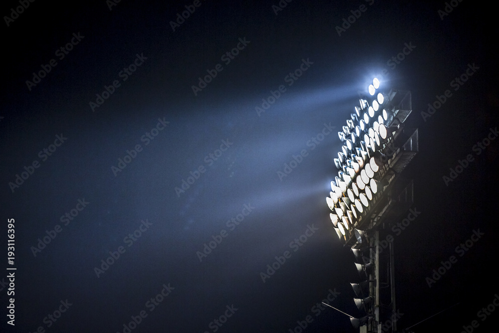Light tower lit at a stadium during nightime. - obrazy, fototapety, plakaty 