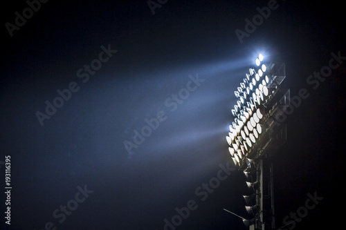 Light tower lit at a stadium during nightime.