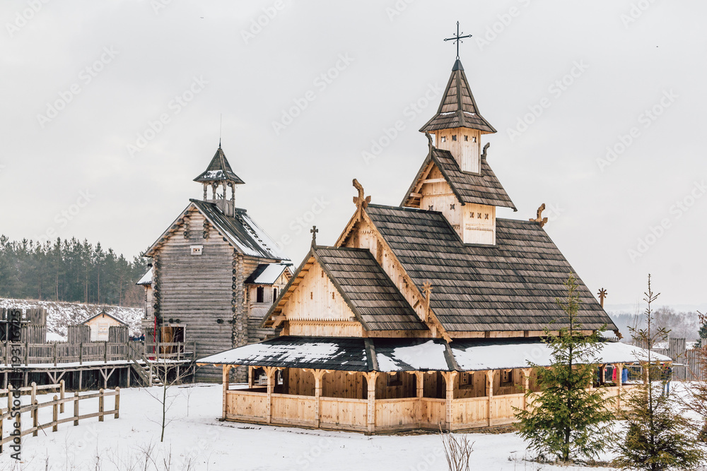 Ancient wooden Slavic church on a snowy landscape. Historical and Architectural Museum in the open air. Kiev, Ukraine.