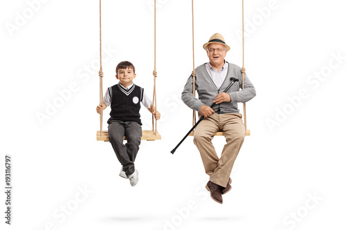 Little schoolboy and a mature man seated on swings