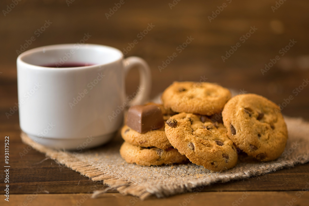 White cup of tea and cookies on dark wooden background White cup of tea and cookies on dark wooden background