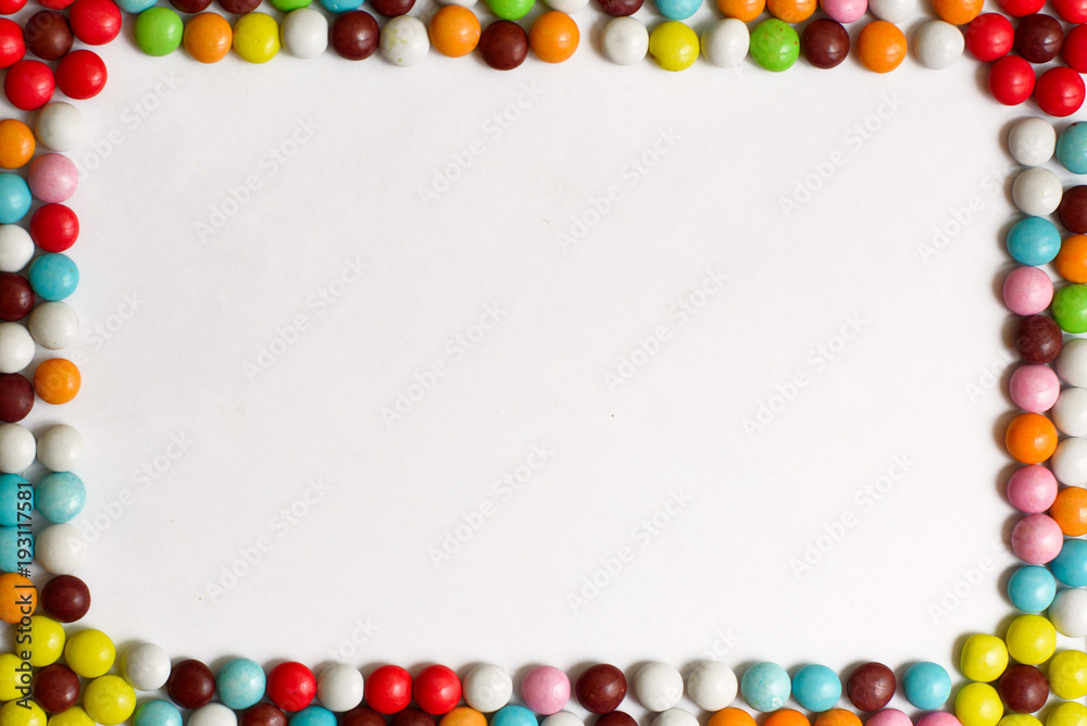 Obraz premium Round chocolate Bonbons covered with colored glaze on white background. Top view. Copy space.