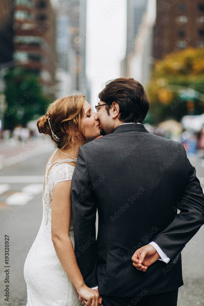Look from behind at wedding couple kissing on the streets of New York Look from behind at wedding couple kissing on the streets of New York