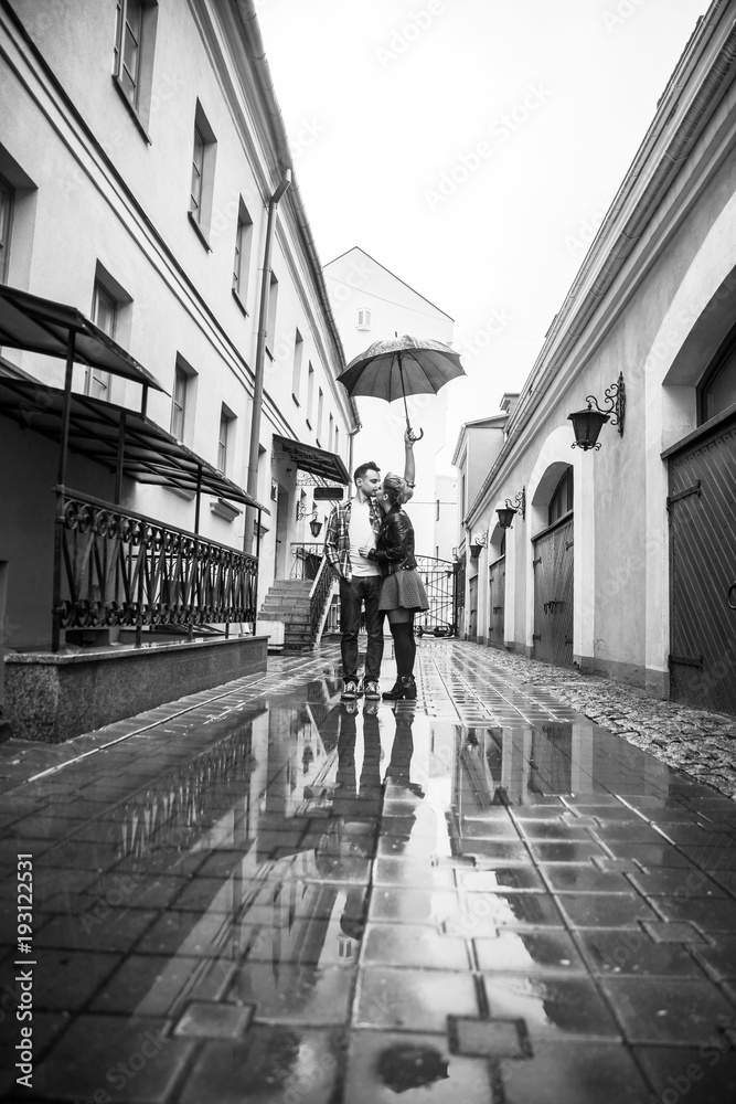 happy, loving couple kissing under an umbrella on a city street on a rainy day