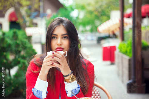 young woman thinking holding coffee on a trendy cafe terrace