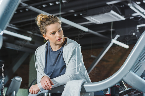 overweight woman leaning on rail of treadmill at gym