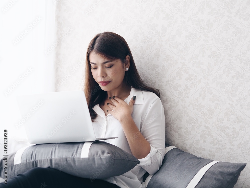 Asian woman working with laptop in bedroom,she's feeling unwell. Asian woman working with laptop in bedroom,she's feeling unwell.