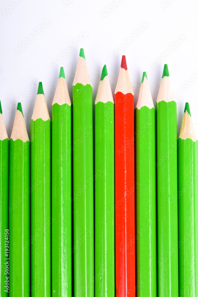 Red pencil standing out from crowd of plenty identical black fellows on white table. Leadership, uniqueness, independence, initiative, strategy, dissent, think different, business success concept Red pencil standing out from crowd of plenty identical black fellows on white table. Leadership, uniqueness, independence, initiative, strategy, dissent, think different, business success concept