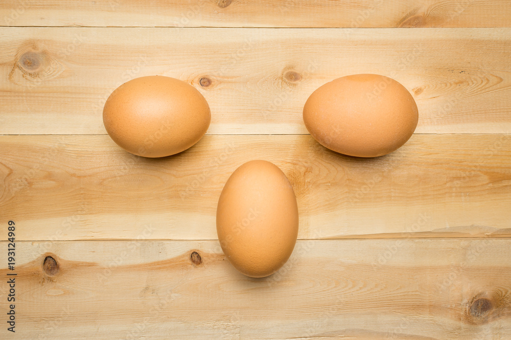Three chicken eggs lie on a wooden board Three chicken eggs lie on a wooden board