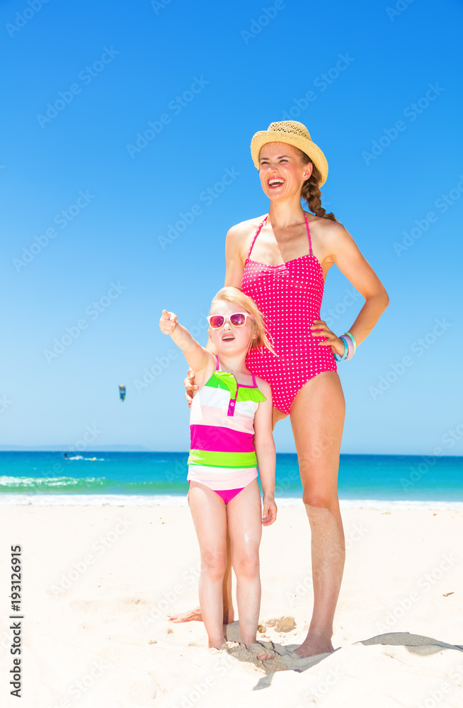 smiling mother and child on seashore pointing at something smiling mother and child on seashore pointing at something