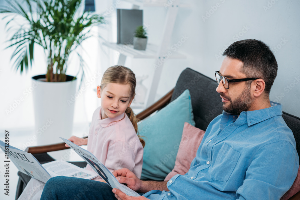side view of father and daughter with newspapers resting on sofa at home side view of father and daughter with newspapers resting on sofa at home