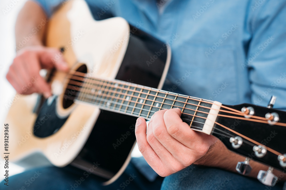 cropped shot of man playing acoustic guitar at home