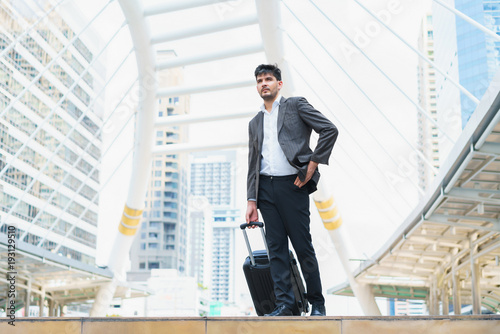 Business man walking at outdoors with luggage in the routine of working with determination and confidence. concept of business trip travel and transportation.