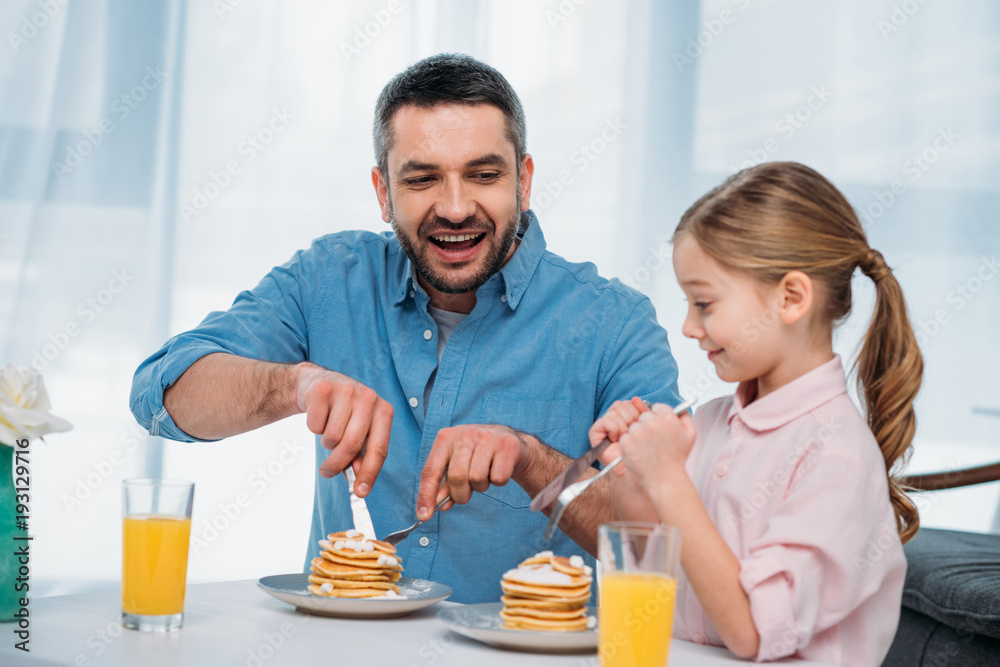 cheerful father and little daughter having breakfast at home cheerful father and little daughter having breakfast at home
