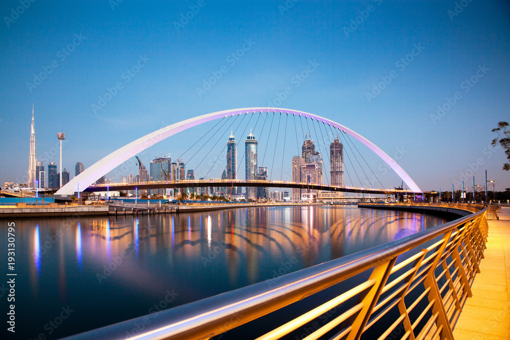 Fototapeta premium Dubaj, Zjednoczone Emiraty Arabskie - luty 2018: Kolorowy zachód słońca nad drapaczami chmur w centrum Dubaju i nowo wybudowanym mostem tolerancji, patrząc z kanału wodnego w Dubaju.