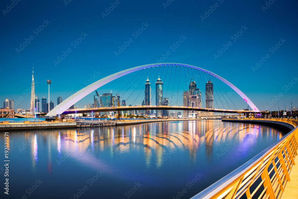 Naklejka premium Dubaj, Zjednoczone Emiraty Arabskie - luty 2018: Kolorowy zachód słońca nad drapaczami chmur w centrum Dubaju i nowo wybudowanym mostem tolerancji, patrząc z kanału wodnego w Dubaju.