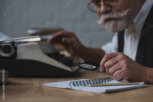 close-up shot of senior writer rewriting manuscript with typing machine