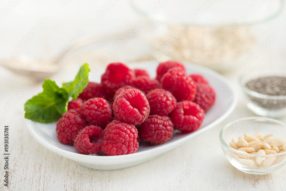 raspberries on white dish on wooden background raspberries on white dish on wooden background