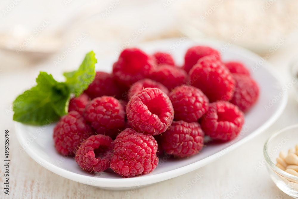 raspberries on white dish on wooden background raspberries on white dish on wooden background