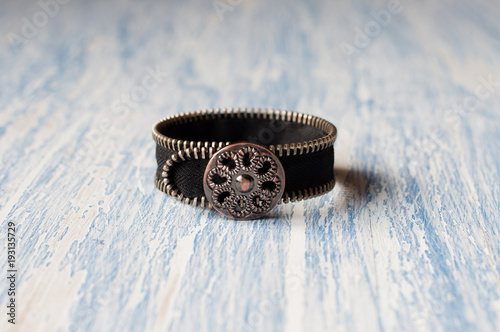 Black bracelet handmade on a blue background with space for copy photo