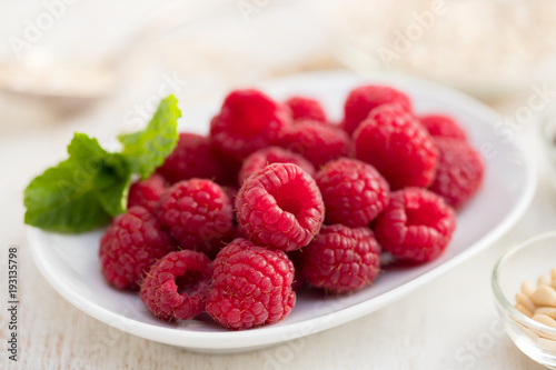 raspberries on white dish on wooden background