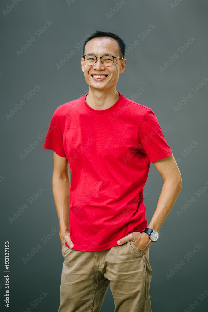 An image of a attractive,middle aged man leaning on a gray wall while smiling in fornt of the camera. He is wearing a casual red tee and a khaki pants that made him look so simple and cool. An image of a attractive,middle aged man leaning on a gray wall while smiling in fornt of the camera. He is wearing a casual red tee and a khaki pants that made him look so simple and cool.