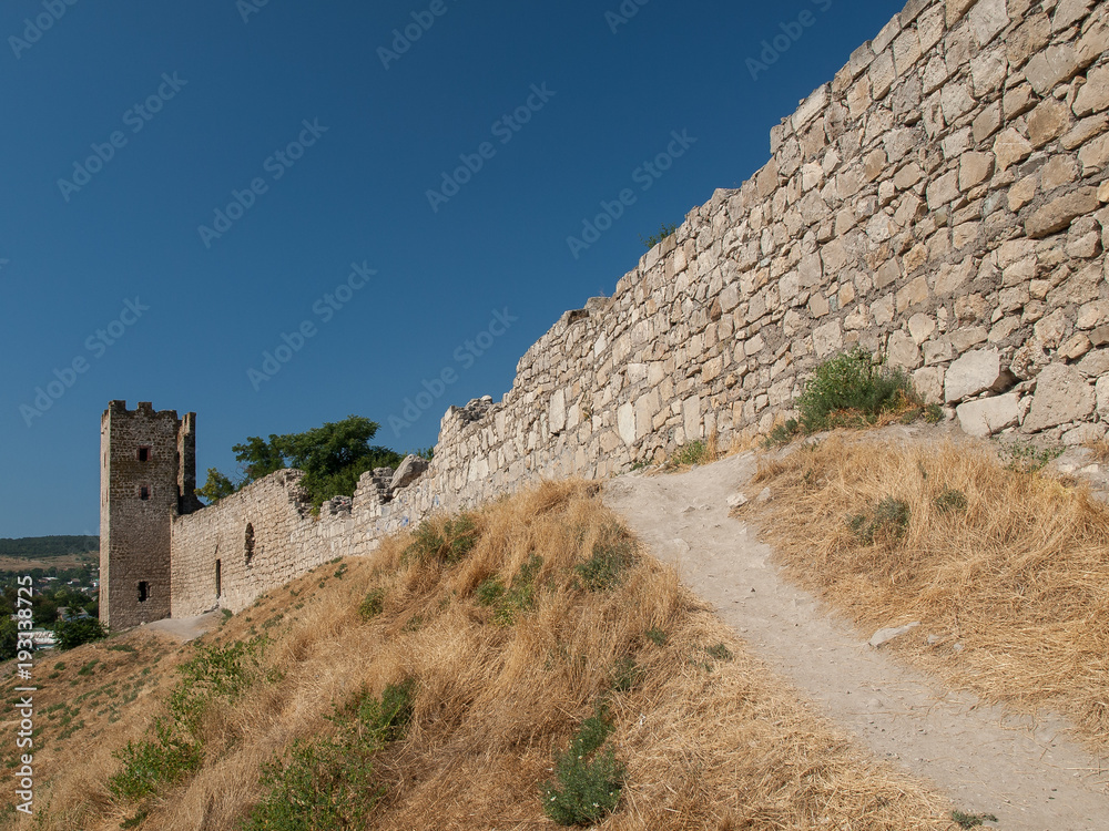 Stone tower of an ancient fortress with adjoining rocky walls