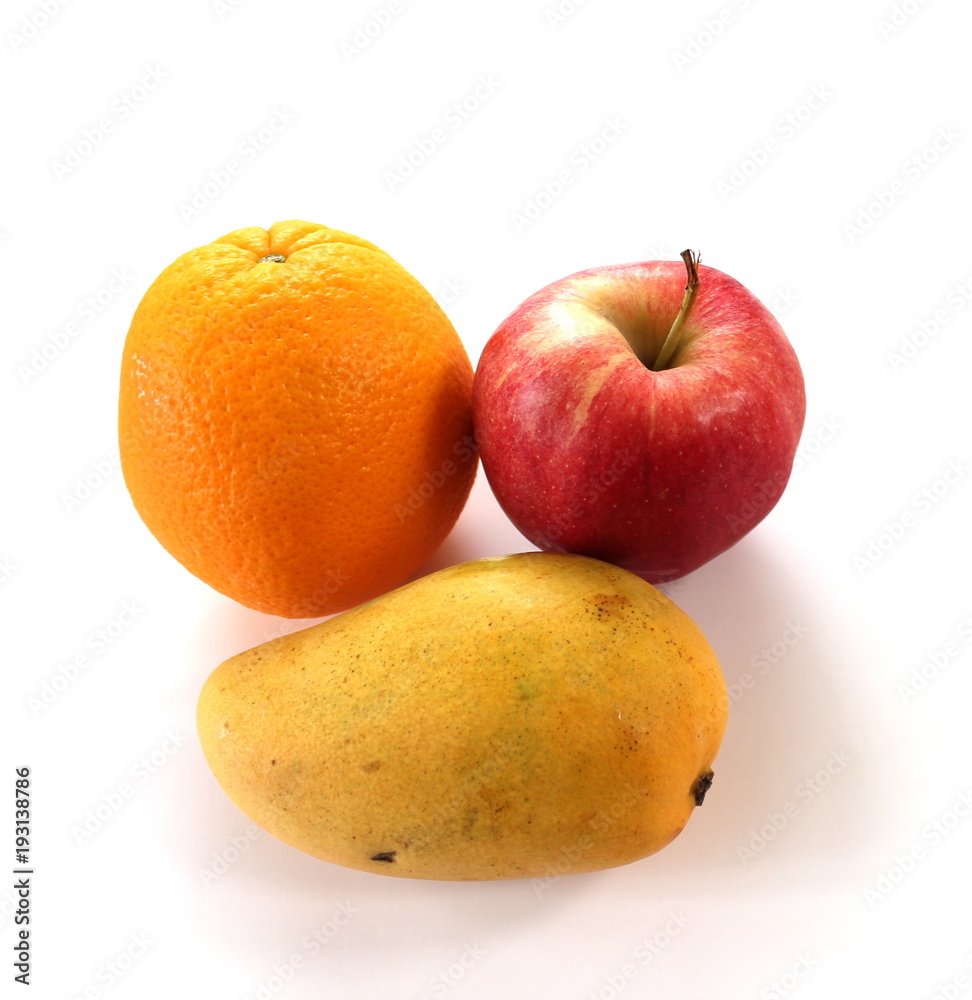 An orange, apple and a mango. White background with copy space. An orange, apple and a mango. White background with copy space.