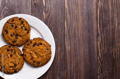 Homemade oatmeal cookies on a white plate. Wooden background. Space for text