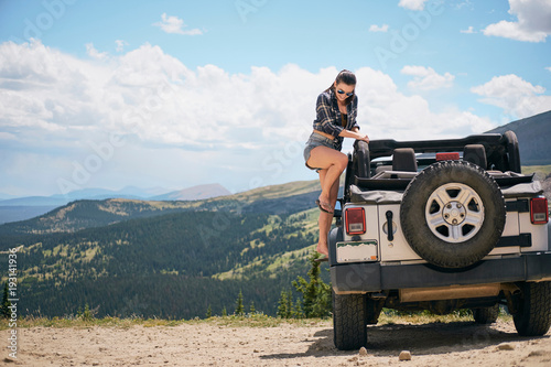 Young woman on road trip climbing into parked off road vehicle, Breckenridge, Colorado, USA