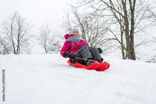 Girl sledging downhill an having fun