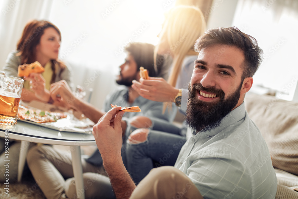 Smiling friends eating pizza and drinking beer at home Smiling friends eating pizza and drinking beer at home