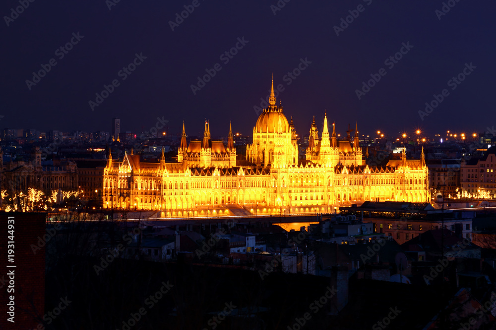 Obraz premium Panorama of Neo-Gothic Orszaghaz Parliament Building Hungarian legislative body seat at dusk illuminated by glowing yellow light on Danube riverbank Kossuth Square Pest Budapest Hungary Central Europe