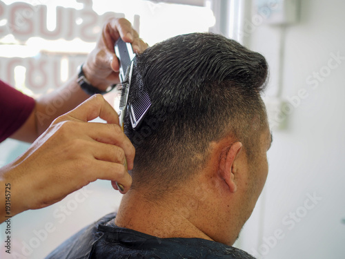 man getting haircut at barber shop. Hairdresser cutting hair of customer at salon. © kridtanat