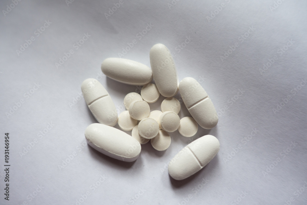 Handful of white oblong caplets of calcium citrate and round tablets of vitamin K2 Handful of white oblong caplets of calcium citrate and round tablets of vitamin K2
