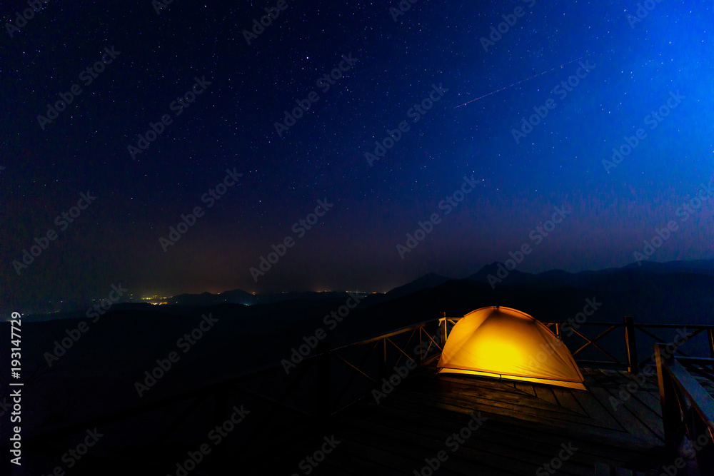 Lonely camping on the mountain under the stars and blue sky.